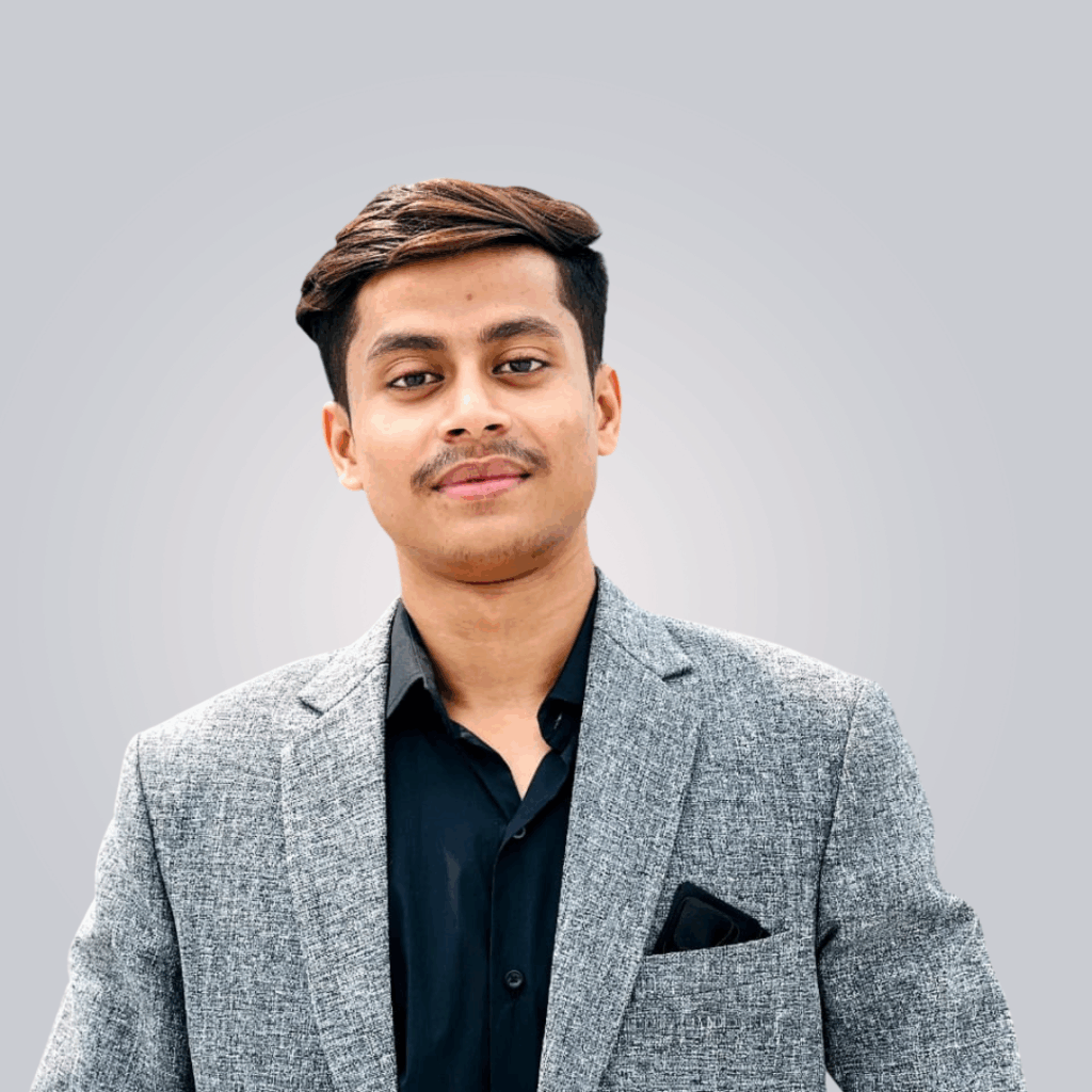 Young man in a gray blazer and black shirt poses confidently.
